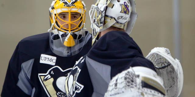 Pittsburgh Penguins goalie Marc-Andre Fleury, who has been out of action with concussion symptoms, talks with goalie Jeff Zatkoff during a practice session for the NHL hockey playoffs against the New York Rangers, Monday, April 11, 2016, at their practice facility in Cranberry, Pa. (AP Photo/Keith Srakocic)
