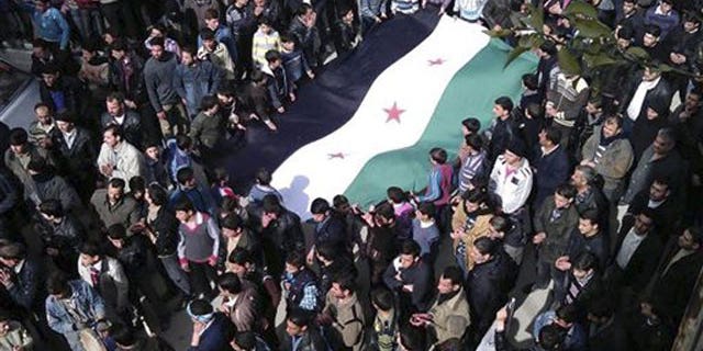 In this Feb. 24, 2012 citizen journalism image provided by the Local Coordination Committees in Syria and accessed on Saturday, Feb. 25, 2012, anti-Syrian regime demonstrators carry a large Syrian revolution flag during a demonstration, in Damascus, Syria.
