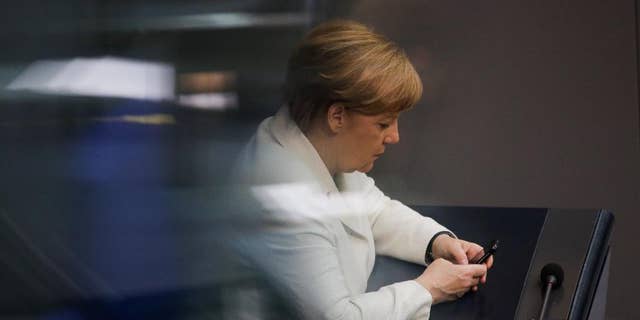 German Chancellor Angela Merkel uses her mobile devices as she attends a debate about a package of new measures to help fight terrorism at the German parliament Bundestag in Berlin, Thursday, June 9, 2016. (AP Photo/Markus Schreiber)