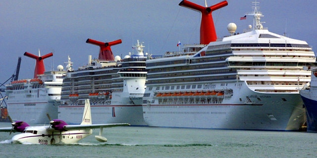 An aircraft is shown landing in front of Carnival cruise ships docked January 6, 2002, at the Port of Miami in Miami, Florida. 