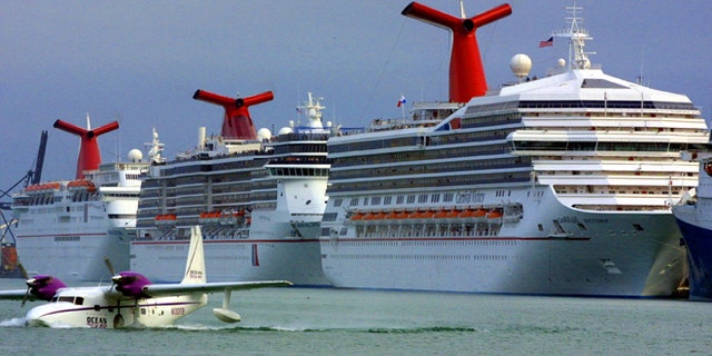 An aircraft is shown landing in front of Carnival cruise ships docked January 6, 2002, at the Port of Miami in Miami, Florida.