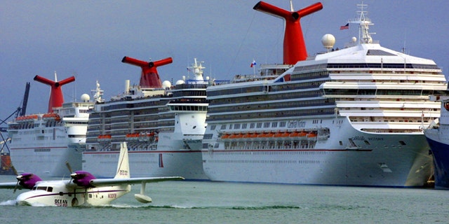 An aircraft is shown landing in front of Carnival cruise ships docked January 6, 2002, at the Port of Miami in Miami, Florida. 