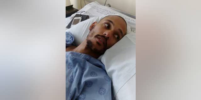 An injured Darryn August lays in his hospital bed in Cape Town, Wednesday, May 11, 2016 after he was thrown from a moving train by assailants last week. He is now paralyzed from the waist down, prompting a flow of donations for what is expected to be a long, costly rehabilitation. (AP Photo/Edwin Brooks)