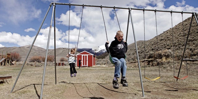 In this April 30, 2013 , photo, siblings, Tyrell and Shelby Schrepfer swing at recess in Polaris, Montana. The pair are students at Polaris School, which only serves four students. (AP Photo/Kathryn Haake)