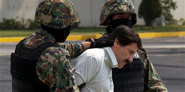 Joaquin "El Chapo" Guzman is escorted to a helicopter in handcuffs by Mexican navy marines at a navy hanger in Mexico City, Mexico, Saturday, Feb. 22, 2014.