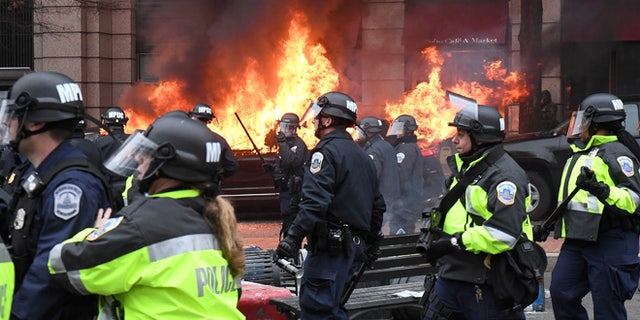 Police officers move protestors away from a car that was set on fire during protests near the inauguration of President Donald Trump in Washington, DC, U.S., January 20, 2017.  REUTERS/Bryan Woolston     TPX IMAGES OF THE DAY - RTSWL62