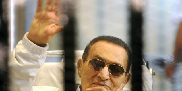 Former Egyptian President Hosni Mubarak waves to his supporters from behind bars as he attends a hearing in his retrial on appeal in Cairo, Egypt, Saturday, April 13, 2013. Egypt's highest court in January ordered a retrial for Mubarak, for failing to stop the killing of 900 protestors in the 2011 unrest that ousted him, after accepting an appeal against his life sentence, citing procedural failings. A high-level inquiry into the deaths of the nearly 900 protesters killed in the uprising, parts of which were released exclusively to The Associated Press last month, could weigh heavily in the retrial. (AP Photo)