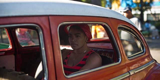 A woman waits in a classic American car that's used as a shared taxi by commuters in Havana, Cuba, early Thursday, Dec. 18, 2014. After a half-century of Cold War acrimony, the United States and Cuba abruptly moved on Wednesday to restore diplomatic relations _ a historic shift that could revitalize the flow of money and people across the narrow waters that separate the two nations. (AP Photo/Ramon Espinosa)
