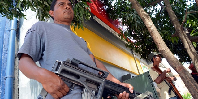 A group of armed vigilantes stand at the entrance to the town of Tierra Colorada, Mexico, Wednesday, March 27, 2013. Hundreds of armed vigilantes have taken control of this town on a major highway in the Pacific coast state of Guerrero, arresting local police officers and searching homes after a vigilante leader was killed. Several opened fire on a car of Mexican tourists headed to the beach for Easter week. (AP Photo/Bernandino Hernandez)