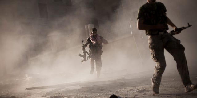 Sept. 7, 2012: In this photo, Free Syrian Army fighters run after attacking a Syrian Army tank during fighting in the Izaa district in Aleppo, Syria.