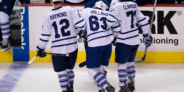Toronto Maple Leafs' Dave Bolland, center, is helped off the ice by Mason Raymond, left, and David Clarkson during the second period of an NHL hockey game against the Vancouver Canucks in Vancouver, British Columbia, on Saturday, Nov. 2, 2013. (AP Photo/The Canadian Press, Darryl Dyck)