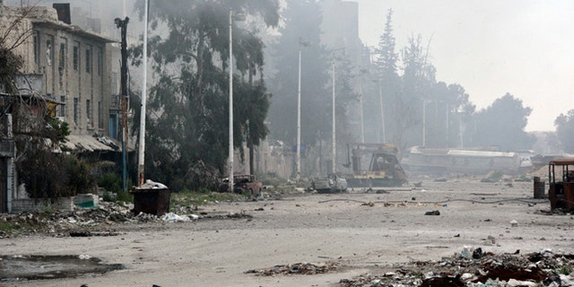 In this photo released by the Syrian official news agency SANA, damaged and blocked street where clashes erupted between the Syrian government forces and rebels, near the Abbassiyin square, east Damascus, Syria, Monday March 20, 2017. Syrian government forces on Monday regained control of parts of Damascus that were attacked and captured by rebels and militants the previous day, with the two-day fighting leaving dozens dead on both sides, the military and an activist group said. (SANA via AP)