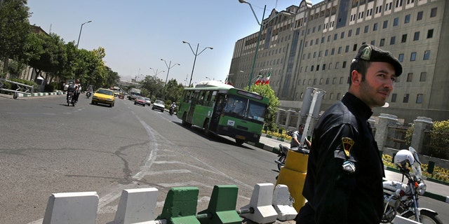 A police officer stands guard as vehicles drive in front of Iran's parliament building in Tehran, Iran, Thursday, May 8, 2017.