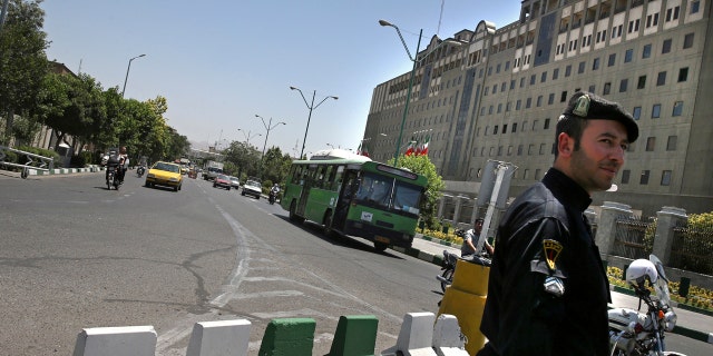 A police officer stands guard as vehicles drive in front of Iran's parliament building in Tehran, Iran, Thursday, May 8, 2017.