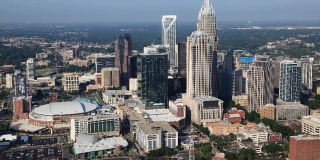 In this Aug. 16, 2012 file photo, the Time Warner Cable Arena is shown on left of downtown Charlotte, N.C. To much of the world, Charlotte is the Queen City, a gleaming downtown, state-of-the-art stadiums, sparkling new mass transit, the nation's banking capital. But a very different Charlotte came into the spotlight in the past few days. Move outside the city's core and there are neighborhoods like the one where a police officer shot and killed a black man, Keith Scott, Sept. 20, 2016, setting off violent protests.(AP Photo/Chuck Burton)