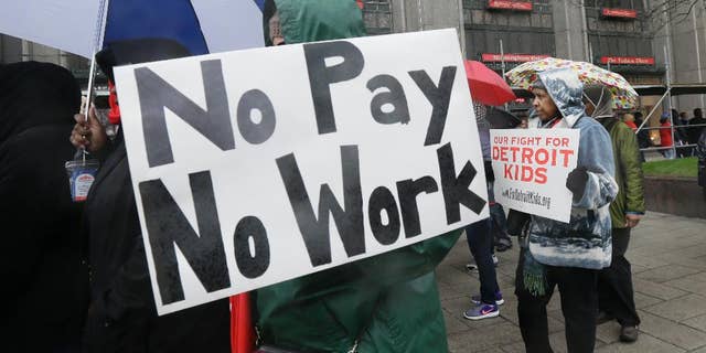 Detroit teachers march outside the district headquarters, Monday, May 2, 2016, in Detroit. Nearly all of Detroit's public schools were closed Monday and more than 45,000 students missed classes after about half the district's teachers called out sick to protest the possibility that some of them will not get paid over the summer if the struggling district runs out of cash. (AP Photo/Carlos Osorio)