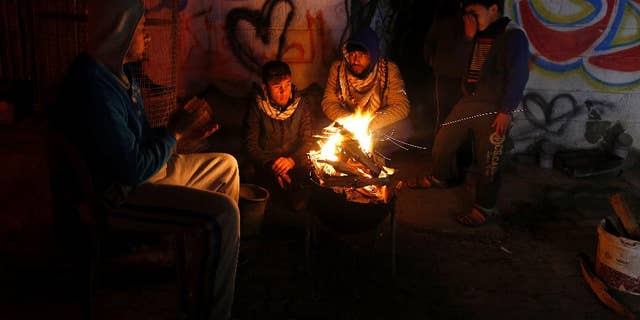 FILE -- In this Jan. 25, 2016 file photo, Palestinians, who get only several hours of electricity a day, sit around a fire outside their home in Gaza City. Israel said Thursday, April 27, 2017, that it was informed that the Palestinian self-rule government in the West Bank will stop paying for electricity Israel sells to the Gaza Strip. Abbas has threatened to exert financial pressure against political rival Hamas to cede control of Gaza, a territory it seized from him in 2007. Gazans now have electricity for only six hours a day. (AP Photo/Hatem Moussa, File)