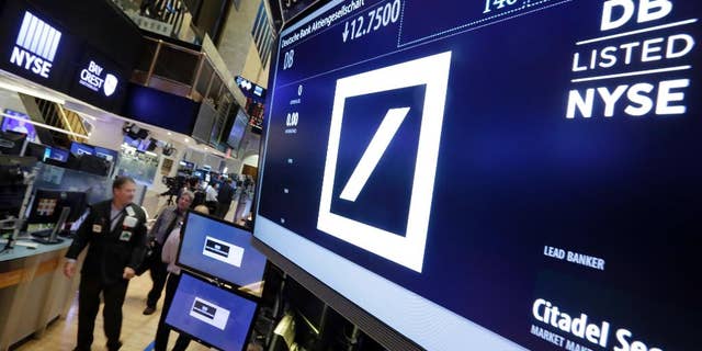 Traders walk by the post where Deutsche Bank is traded on the floor of the New York Stock Exchange, Monday, Sept. 26, 2016. Shares in Deutsche Bank are down sharply after a report that the German government won't intervene with U.S. officials who are pressing the bank to pay $14 billion to settle an investigation into its sales of mortgage-backed securities. (AP Photo/Richard Drew)