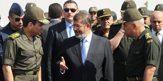 FILE - In this Wednesday, Oct. 10, 2012 file photo released by the Egyptian Presidency, then Egyptian President Mohammed Morsi, center, speaks with Minister of Defense, Lt. Gen. Abdel-Fattah el-Sissi, left, at a military base in Ismailia, Egypt. An Egyptian court has set Nov. 4, 2013, as the start date for the trial of ousted President Mohammed Morsi on charges of incitement to murder for the killings of opponents who were rallying outside his palace while he was in office. Morsi, ousted in a popularly-backed military coup in July, has been held incommunicado since. (AP Photo/Egyptian Presidency)