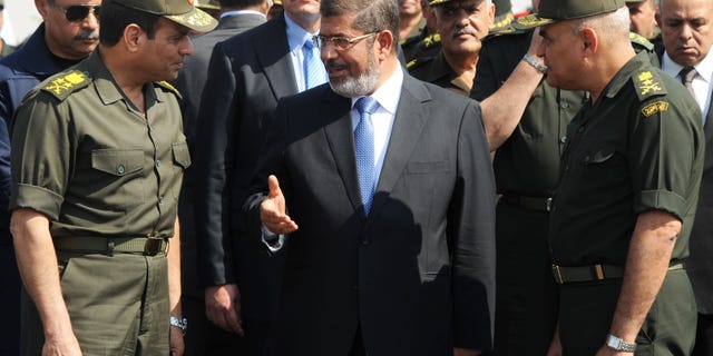 FILE - In this Wednesday, Oct. 10, 2012 file photo released by the Egyptian Presidency, then Egyptian President Mohammed Morsi, center, speaks with Minister of Defense, Lt. Gen. Abdel-Fattah el-Sissi, left, at a military base in Ismailia, Egypt. An Egyptian court has set Nov. 4, 2013, as the start date for the trial of ousted President Mohammed Morsi on charges of incitement to murder for the killings of opponents who were rallying outside his palace while he was in office. Morsi, ousted in a popularly-backed military coup in July, has been held incommunicado since. (AP Photo/Egyptian Presidency)