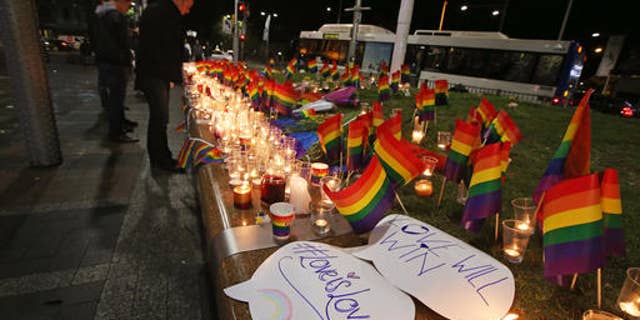 An impromptu memorial is set up in Sydney, Monday, June 13, 2016, following the Florida mass shooting at the Pulse Orlando nightclub where police say a gunman wielding an assault-type rifle opened fire, killing at least 50 people and wounding dozens. Australian Prime Minister Malcolm Turnbull said that the Orlando mass shooting was "an attack on all of us â on all our freedoms, the freedom to gather together, to celebrate, to share time with friends." (AP Photo/Rick Rycroft)