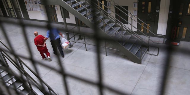 A guard escorts an immigrant detainee from his cell back into the general population at the Adelanto Detention Facility on November 15, 2013 in Adelanto, California. (Photo by John Moore/Getty Images)