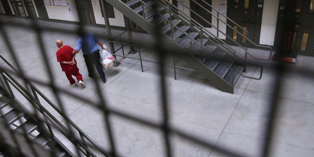 A guard escorts an immigrant detainee from his cell back into the general population at the Adelanto Detention Facility on November 15, 2013 in Adelanto, California. (Photo by John Moore/Getty Images)