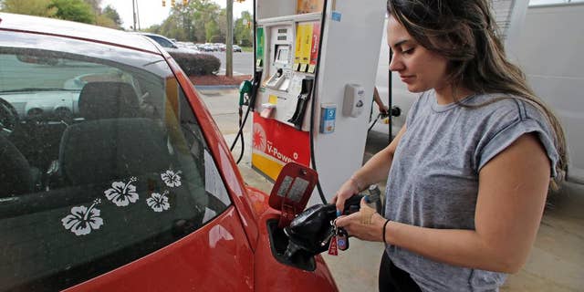 FILE - In this April 6, 2015 file photo, Lucy Perez, of Charlotte, N.C., pumps gas at a station in Matthews, N.C. The University of Michigan issues its monthly index of consumer sentiment for April on Friday, May 1, 2015. (AP Photo/Chuck Burton, File)