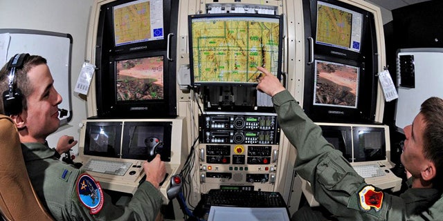 Airman 1st Class Caleb Force assists 1st Lt. Jorden Smith, a MQ-1B Predator pilot, in locating simulated targets during a training mission conducted inside the simulators at Creech Air Force Base, Nev.