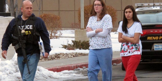 Police escort hospital staff away from a medical office building in Reno, Nev., on Tuesday, Dec. 17, 2013. A suicidal gunman killed one person and critically wounded two others before turning the gun on himself on the grounds of Renown Regional Medical Center Tuesday. (AP Photo/Scott Sonner).