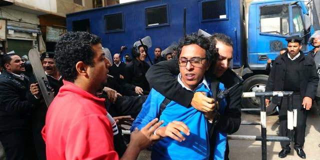 FILE - In this Nov. 30, 2013 file photo, a protester is detained near a Cairo court where supporters of the April 6 youth group gathered to condemn the detention of 24 activists arrested the previous week while taking part in a protest that was not authorized by authorities, in Cairo. Egypt. A defense lawyer said Tuesday, Jan. 27, 2015 that Egypt’s highest appeal court has upheld the convictions and three-year prison sentences handed down to Ahmed Maher, Ahmed Douma and Mohammed Adel, three of Egypt’s most prominent political activists for violating a draconian protest law. (AP Photo/Ahmed Omar, File)