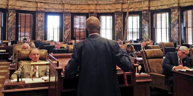 Sen. Hillman Frazier, D-Jackson, brandishes a sheathed sword Tuesday, March 29, 2016, during debate over House Bill 786, at the Capitol in Jackson, Miss. Frazier opposed the bill, which would grant immunity to trained church security teams that shoot people trying to commit violent crimes. Frazier said the bill went against Christian teaching, recounting the story of Jesus healing a servant of a high priest after a disciple cut off the servant’s ear with a sword. (AP Photo/Jeff Amy)