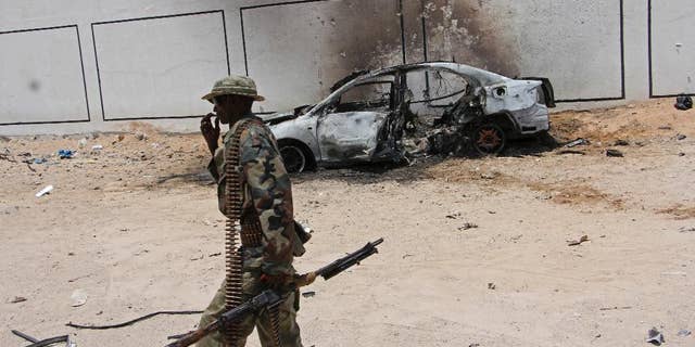 A Somali soldier walks near the wreckage of a car bomb blast near Aden Abdule international airport in Mogadishu, Somalia, Sunday, April, 16, 2017. A Somali police officer says a car bomb detonated near the Somali capital's airport. (AP Photo/Farah Abdi Warsameh)