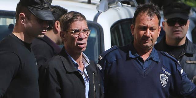 EgyptAir plane hijacking suspect Seif Eddin Mustafa, second left, is escorted by Cyprus police officers as he leaves a court after a remand hearing as authorities investigate him on charges including hijacking, illegal possession of explosives and abduction in the Cypriot coastal town of Larnaca Wednesday, March 30, 2016. Mustafa described as "psychologically unstable" hijacked a flight Tuesday from Egypt to Cyprus and threatened to blow it up. His explosives turned out to be fake, and he surrendered with all passengers released unharmed after a bizarre six-hour standoff. (AP Photo/Petros Karadjias)