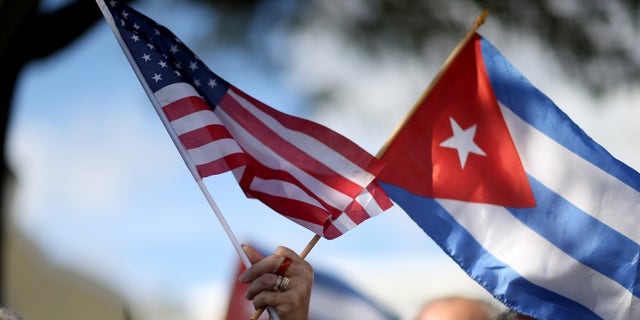 MIAMI, FL - DECEMBER 20: A protester holds an American flag and a Cuban one as she joins with others opposed to U.S. President Barack Obama's announcement earlier in the week of  a change to the United States Cuba policy stand together at Jose Marti park on December 20, 2014 in Miami, Florida. President Obama announced a move toward normalizing the relationship with Cuba after a swap of prisoners took place.  (Photo by Joe Raedle/Getty Images)