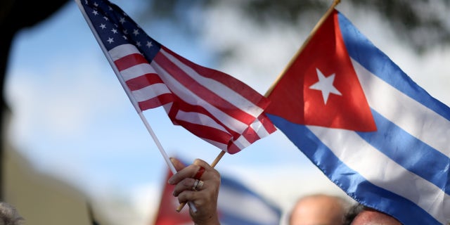 MIAMI, FL - DECEMBER 20: A protester holds an American flag and a Cuban one as she joins with others opposed to U.S. President Barack Obama's announcement earlier in the week of a change to the United States Cuba policy stand together at Jose Marti park on December 20, 2014 in Miami, Florida. President Obama announced a move toward normalizing the relationship with Cuba after a swap of prisoners took place. (Photo by Joe Raedle/Getty Images)