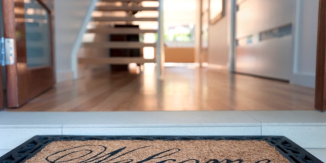 Close up of a welcome mat in front of an inviting house.