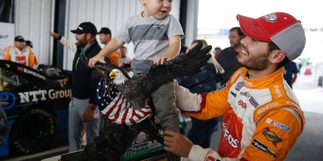 Kyle Larson, right, plays with his son Owen Larson and the trophy after he won the rain-shortened NASCAR Xfinity series auto race at Pocono Raceway, Saturday, June 4, 2016, in Long Pond, Pa. Larson led when the rain hit 53 laps into the scheduled 100-lap race and the race was called 1 hour, 35 minutes after the red flag came out. (AP Photo/Matt Slocum)