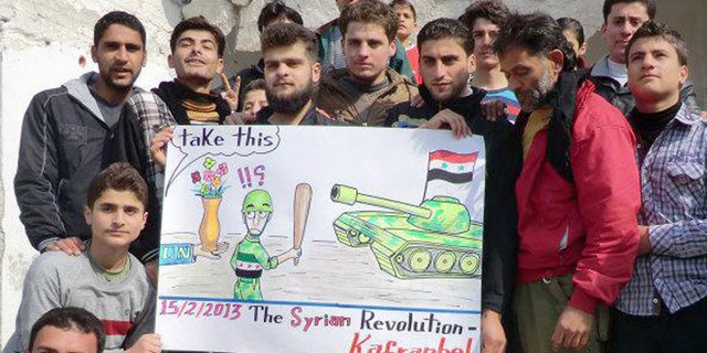 This citizen journalism image provided by Edlib News Network, ENN, which has been authenticated based on its contents and other AP reporting, shows anti-Syrian regime protesters holding a caricature placard during a demonstration, at Kafr Nabil town, in Idlib province, northern Syria, Friday, Feb. 15, 2013. Heavy fighting for control of the international airport in the northern Syrian city of Aleppo and a major military air base nearby has killed some 150 rebels and government soldiers over the past two days, activists said Friday. (AP Photo/Edlib News Network ENN)