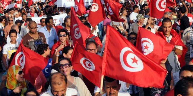 Tunisians wave their national flag as they march outside the National Assembly in Tunis on September 7, 2013, to mark the 40th day since the assassination of opposition politician Mohamed Brahmi.
