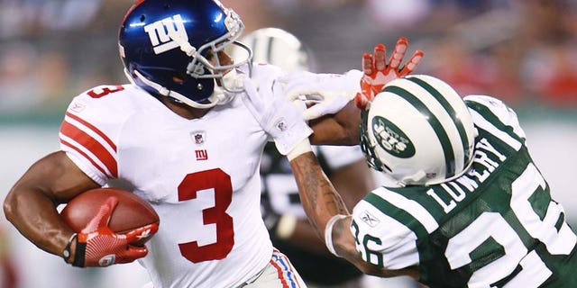 New York Giants Victor Cruz fights off Jets defender.