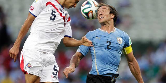 Costa Rica's Celso Borges (5) heads the ball past Uruguay's Diego Lugano (2) during the group D World Cup soccer match between Uruguay and Costa Rica at the Arena Castelao in Fortaleza, Brazil, Saturday, June 14, 2014. (AP Photo/Fernando Llano)