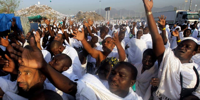 FILE - In this Monday, Oct. 14, 2013 file photo, Muslim pilgrims raise their hands to receive umbrellas in front of a rocky hill called the Mountain of Mercy, on the Plain of Arafat near the holy city of Mecca. Some pilgrims who go to Saudi Arabia to perform pilgrimage stay on illegally in the kingdom in search of work. Saudi authorities are launching intensive nationwide security sweeps on businesses and setting up checkpoints in efforts to detain and deport an estimated 1.5 million foreign workers without proper documentation. The crackdown reflects wider efforts by the kingdom to clear out slums and create jobs for its local workforce as leaders worry that rising unemployment could feed dissent and challenges to their rule by their own people. (AP Photo/Amr Nabil)