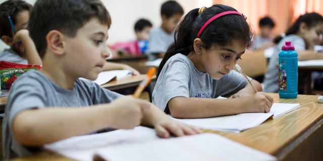RAMALLAH, WEST BANK - SEPTEMBER 17: Palestinian children take notes in their notebooks during a math class on September 17, 2013 in Ramallah, West Bank. The West Bank is a landlocked territory which has an estimated population of 2, 622,544 with Arabs making up almost 80% of the population. It is a disputed territory after Israel captured the land during the six day war in 1967. (Photo by Ilia Yefimovich/Getty Images)