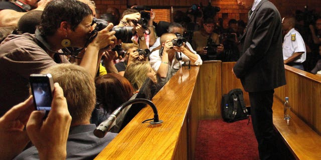 File - In this Wednesday, Feb. 20, 2013 file photo Olympic athlete Oscar Pistorius stands inside a court during his bail hearing at the magistrate court in Pretoria, South Africa. Pistorius will defend himself March 3, 2014 against a charge of premeditated murder in the slaying of his girlfriend Reeva Steenkamp. A South Africa judge has ruled that television stations can broadcast parts of the trial live, but with restrictions on witness testimonies. (AP Photo/Themba Hadebe, File)