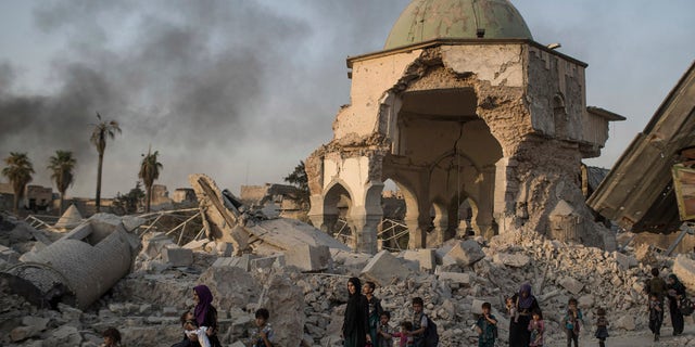 Fleeing Iraqi civilians walk past a heavily damaged al-Nuri mosque as Iraqi forces continue their advance against the Islamic State in this July 4, 2017 file photo.