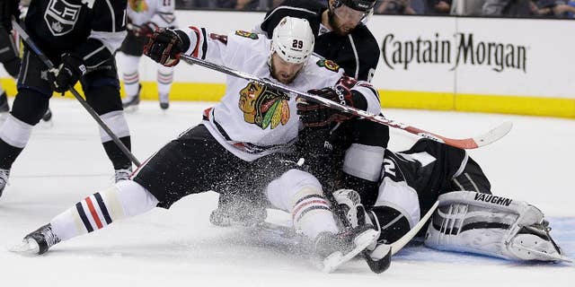 Los Angeles Kings goalie Jonathan Quick, right, blocks a shot by Chicago Blackhawks left wing Bryan Bickell as Kings' Jake Muzzin helps defend during first period of Game 6 of the Western Conference finals of the NHL hockey Stanley Cup playoffs, in Los Angeles on Friday, May 30, 2014. (AP Photo/Chris Carlson)