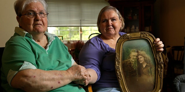 In this photo taken Monday, July 1, 2013 in Chapel Hill, N.C., Shelia Reese, right, sits with her mother Chris Tench holding a portrait of Tench and her father Kenneth F. Reese, a soldier who is still Missing In Action from the Korean War. Tench, who was later remarried, has never known what happened to her husband.