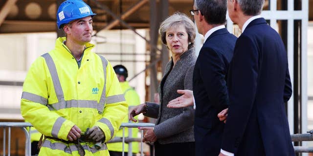 Britain's Prime Minister Theresa May and Chancellor of the Exchequer Philip Hammond, right, during a visit to a construction site in Birmingham, England, where new HSBC bank offices are being built, Monday Oct. 3, 2016. May announced Sunday a timetable for Britain's exit from the European Union, and Treasury chief Hammond warned on Monday of turbulence in the coming years as Britain negotiates its exit from the trading bloc. (Stefan Rousseau / PA via AP)