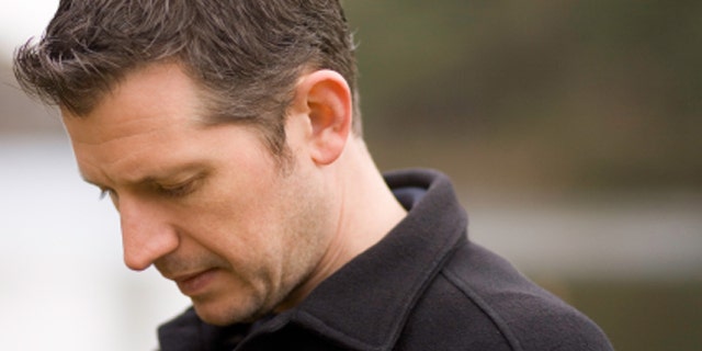 Portrait of adult male, his head down with sadness.